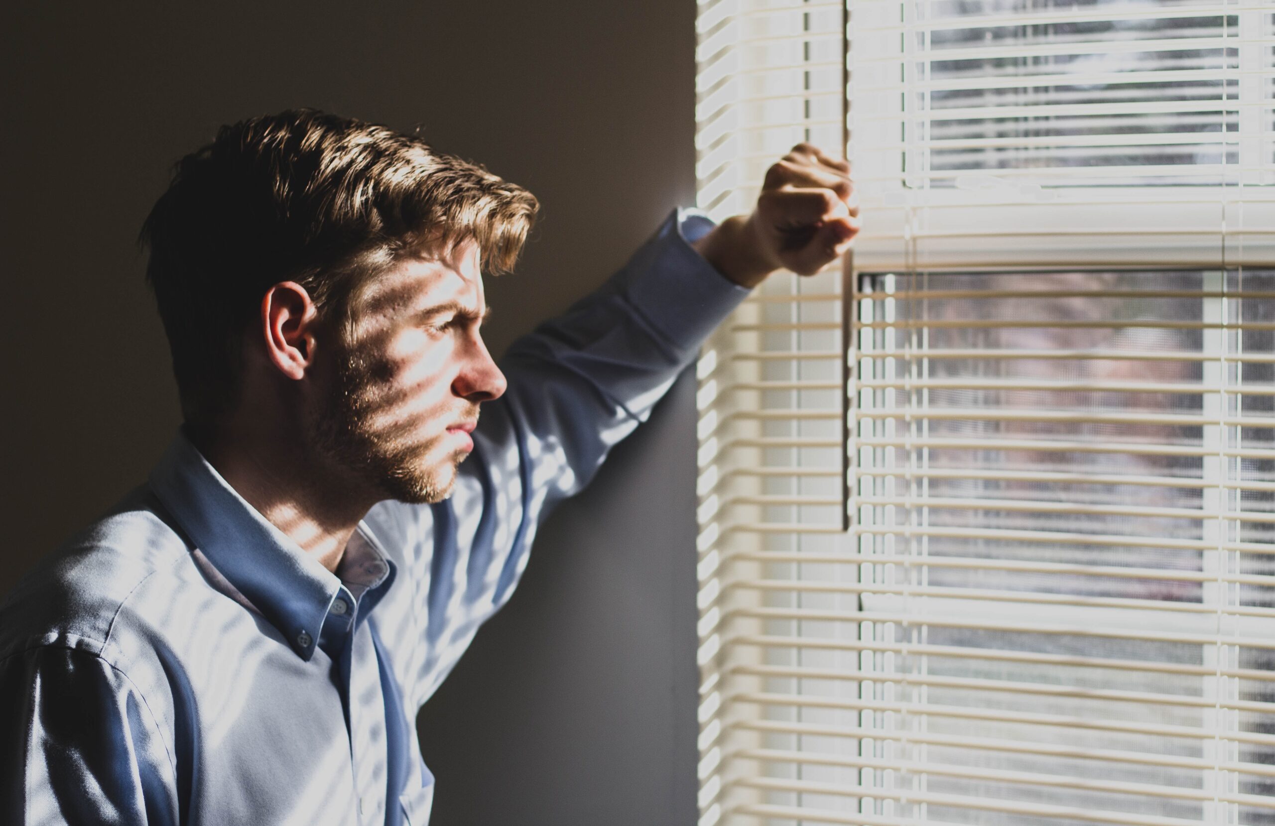 man looking out window sunny